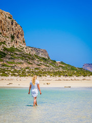 Fototapeta na wymiar Crete, Greece: Blonde beautyful girl enjoying the beautiful crystal clear sea of Balos lagoon. Lagoon of Balos is one of the most visited tourist destinations on west coast of Crete.