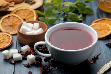 Hot red karkade tea with honey and mint. Autumn or winter soft drink. on blue wooden table