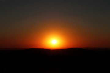 Fototapeta na wymiar A horizontal beautiful orange sunset with black mountains