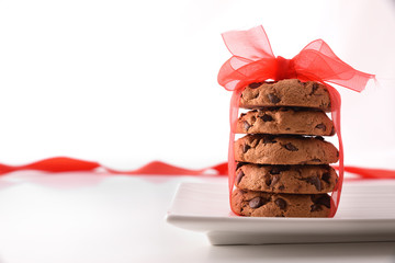 Stack of chocolate cookies with red bow white table front