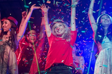 Cheerful young people showered with confetti on a club party. Festival Event Party with People concept.Clubber throwing confetti and drinking.