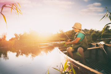 Boy fishing from wooden boat