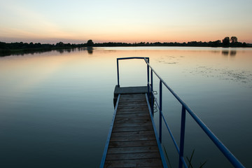 Fototapeta na wymiar Bridge on the lake and cloudless sky after sunset. Staw, Poland