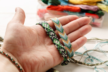 Hand holding different woven friendship bracelet, closeup shot