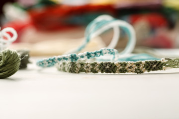 Handcrafted friendship bracelets on a white table with different colored threads