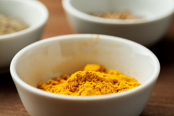 Turmeric poeder in a white bowl on a wooden table, closeup shot