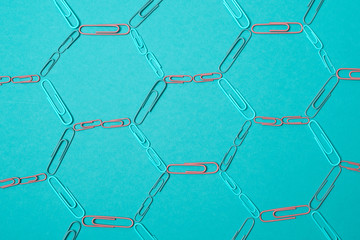 Colorful pastel background created with multiple office supplies like paper clips, binder clips and push pins.