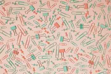Colorful pastel background created with multiple office supplies like paper clips, binder clips and push pins.