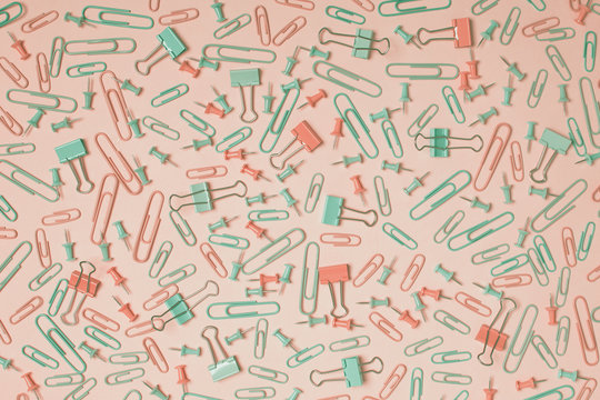Colorful pastel background created with multiple office supplies like paper clips, binder clips and push pins.