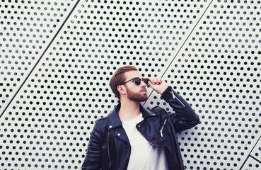 cool fashion men in leather jacket and sunglasses posing on metal background