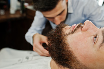 Obraz na płótnie Canvas Handsome bearded man at the barbershop, barber at work.