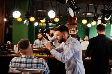 Handsome bearded man at the barbershop, barber at work, making photo on his phone.