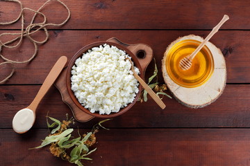 Cottage cheese and cream. Soft cheese and honey on wooden boards. Cottage cheese in pottery and linden flowers. Twine on wooden background. Cream in wooden spoon. Honey on wooden stand. Copy space