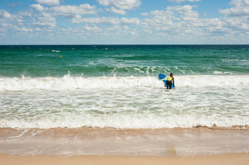 Girl learns to ride a surfboard on the sea in summer. Riding on a surfboard on the waves in a beautiful place. Surfer school on the beach.