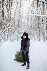 Fototapeta na wymiar Cute boy with a Christmas tree in his hands, winter, new year, forest