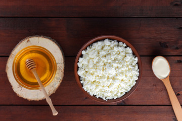 Cottage cheese and cream. Soft cheese and honey on wooden boards. Cottage cheese in pottery. Cream in wooden spoon. Honey on wooden stand. Copy space