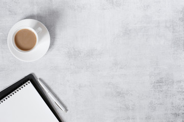 Minimalistic light background with notepad and cup of coffee