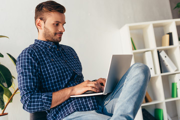 side view of concentrated businessman using laptop in office