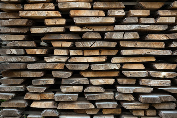 Folded wooden brown and gray planks in a sawmill. Piled alder boards as texture.