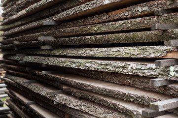 Folded wooden brown and gray planks in a sawmill. Piled alder boards as texture.