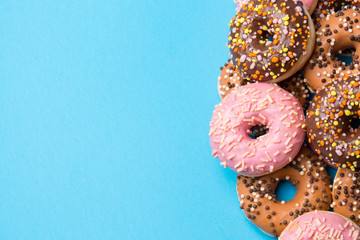 Colorful round donuts on blue background. Flat lay, top view.