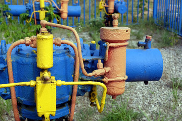 Fototapeta na wymiar Gas unit with faucet and other energy equipment after fence at rural place in summer day