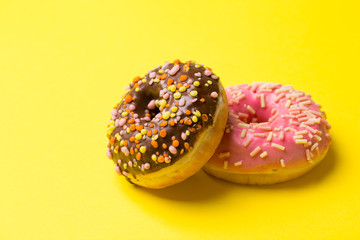 chocolate and pink donuts lie on a yellow background