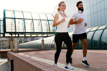 Young fitness couple running in urban area