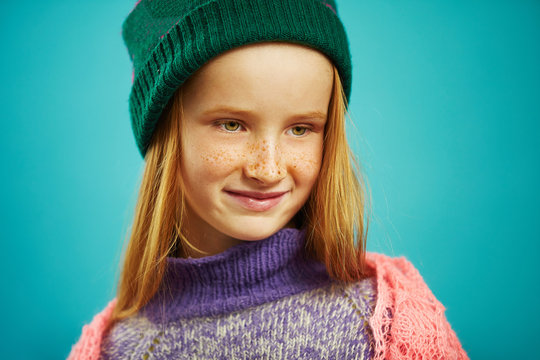 close up image of cute girl in winter sweater and hat on blue isolated.