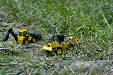 Two excavator toy cars that carry around the grass.