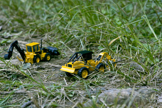 Two excavator toy cars that carry around the grass.