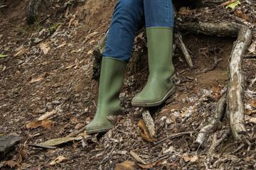 Front view of adult person wearing rain boot in the forest / park, autumn - winter concept