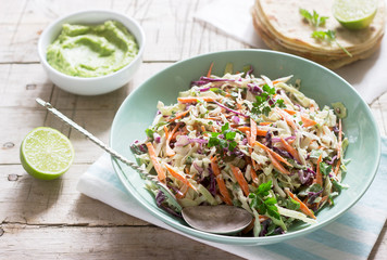 Coleslaw made from cabbage, carrots and various herbs, served with tortillas and guacamala on a wooden background. - obrazy, fototapety, plakaty
