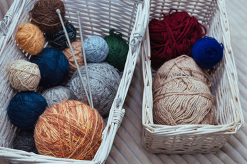 Two white baskets with yarn and knitting needles