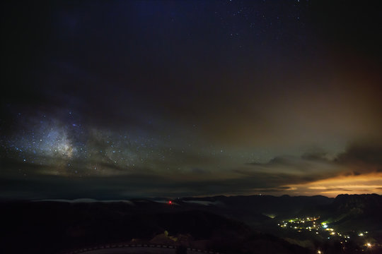 The stars of the Milky Way at night in the sky glow through the clouds. View of outer space in cloudy weather.