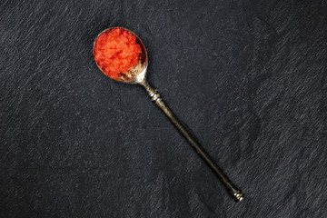 Fototapeta na wymiar An overhead photo of red caviar in a spoon, shot from above on a black background with copyspace