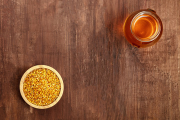 Healthy organic food. An overhead photo of pollen and a jar of honey, shot from above on a dark rustic background with copyspace