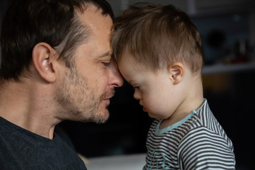 Cute boy with Down syndrome playing with dad on in home living room