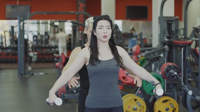Young girl doing exercises in gym with personal trainer