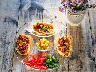 Arrangement with glass tray and greek cheese and different salad on wooden background with flowers