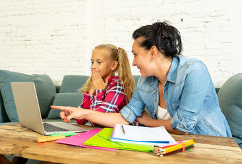 Fototapeta na wymiar Single mum helping her daughter doing her homework with laptop at home
