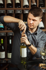 Sommelier opening white wine bottle with corckcrew