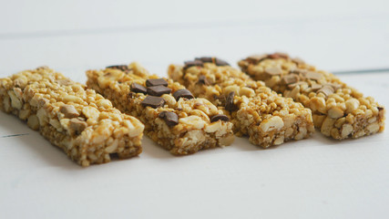 Homemade rustic granola bars with dried fruits on white wooden background