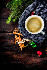 Obraz na płótnie Canvas Spicy cappuccino coffee with for cold winter and autumn day. Xmas morning concept. Classic wooden background with christmas tree and decorations, copy space top view
