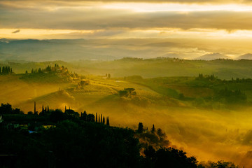 Dawn in a misty valley in the hills in Tuscany, Italy
