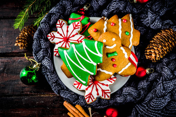 Traditional christmas sweet treats, colorful sugar glazed homemade gingerbread cookies with xmas tree, decoration, spices and coffee latte mud on classic wooden background copy space top view