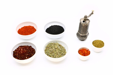 different spices in a white ceramic cup and mill for spices, isolated