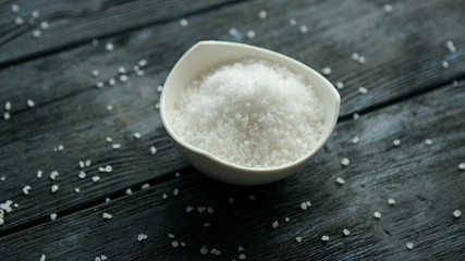 From above closeup shot of bowl full of white salt on wooden table 