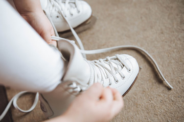 A child ties ice skates in dressing room. Lace. - obrazy, fototapety, plakaty