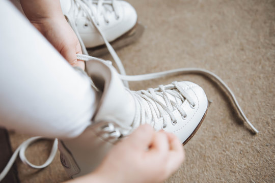 A child ties ice skates in dressing room. Lace.
